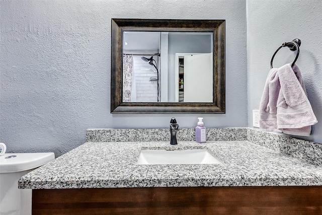 full bathroom with vanity and a textured wall