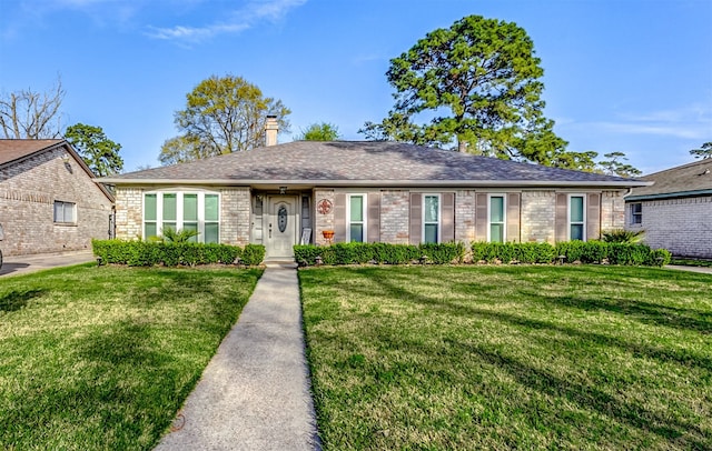 ranch-style home with brick siding, a chimney, a front yard, and a shingled roof