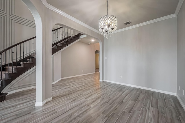 unfurnished living room featuring arched walkways, a chandelier, stairway, and wood finished floors