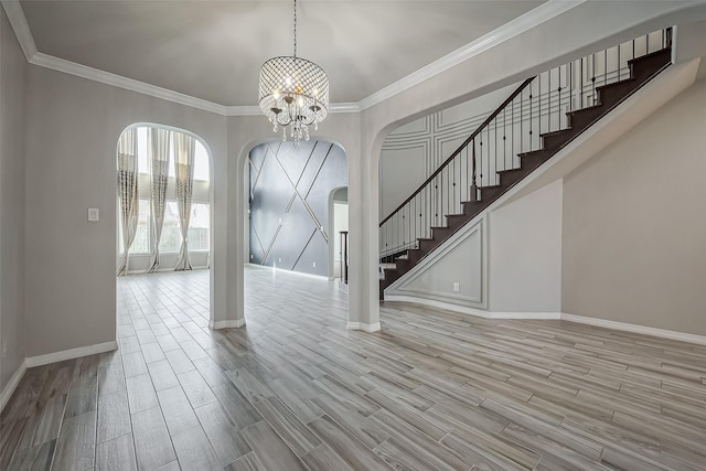 entrance foyer with stairway, a notable chandelier, wood finished floors, and arched walkways