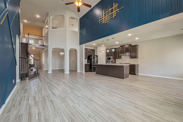 kitchen with arched walkways, appliances with stainless steel finishes, open floor plan, and a ceiling fan