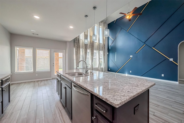 kitchen featuring light stone countertops, ceiling fan, a sink, dishwasher, and light wood-type flooring