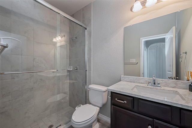 bathroom featuring a stall shower, toilet, vanity, and a textured wall