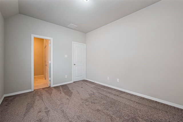 unfurnished bedroom featuring ensuite bath, vaulted ceiling, baseboards, and carpet floors