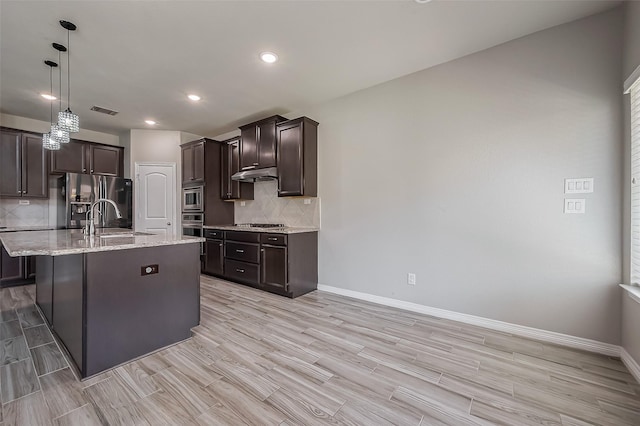 kitchen with visible vents, a sink, stainless steel appliances, dark brown cabinetry, and decorative backsplash