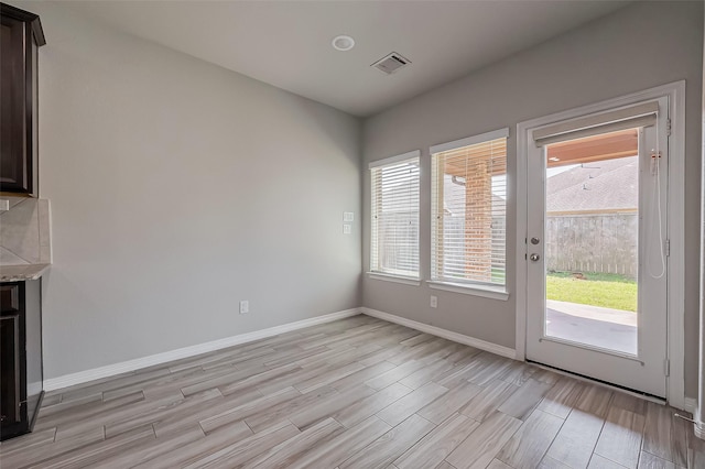 unfurnished dining area featuring visible vents, baseboards, and wood finish floors