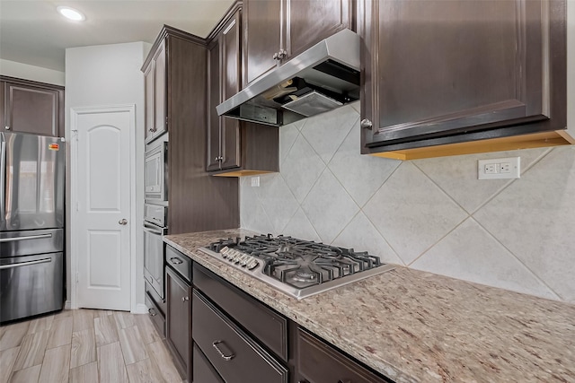 kitchen with under cabinet range hood, appliances with stainless steel finishes, and dark brown cabinets