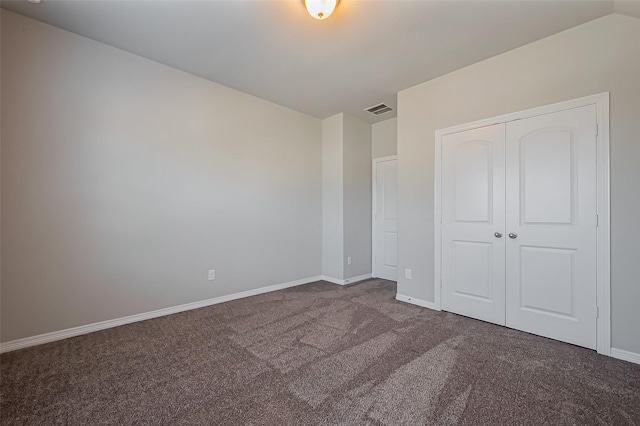 unfurnished bedroom featuring a closet, baseboards, visible vents, and dark carpet