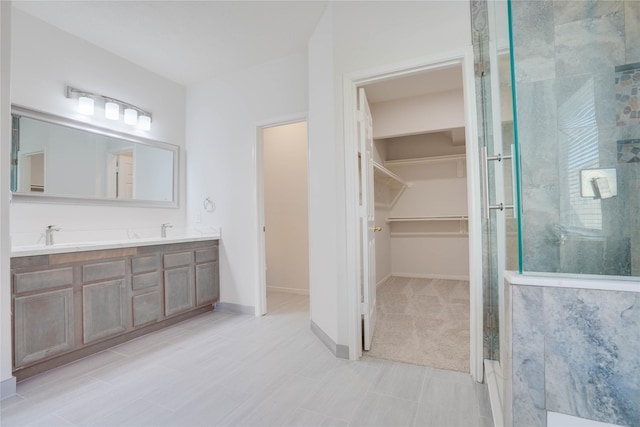 bathroom with baseboards, double vanity, a sink, an enclosed shower, and a walk in closet