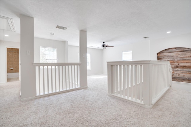 carpeted spare room featuring a ceiling fan, visible vents, attic access, recessed lighting, and a textured ceiling