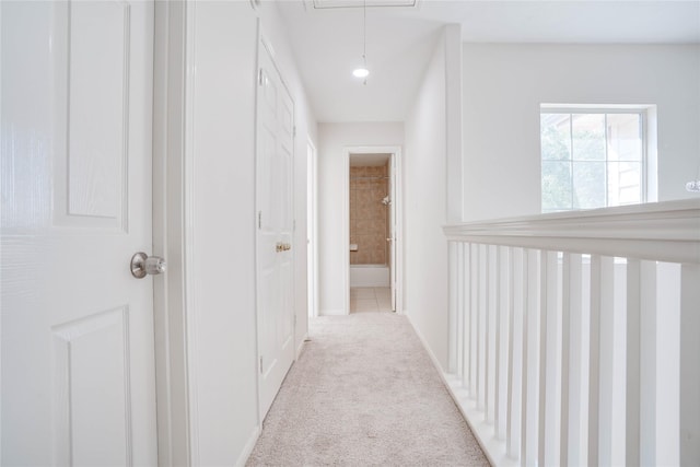 hall featuring attic access and light carpet