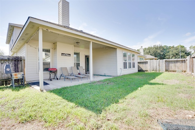 back of property featuring a patio area, a fenced backyard, a lawn, and a chimney