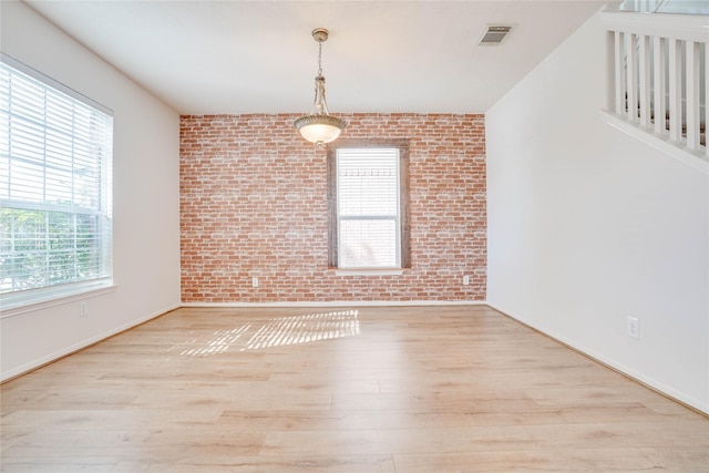 spare room featuring visible vents, brick wall, and wood finished floors