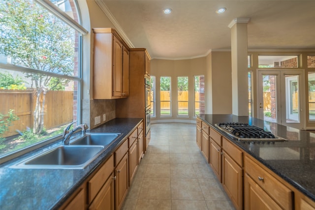 kitchen featuring crown molding, tasteful backsplash, stainless steel gas cooktop, and a sink