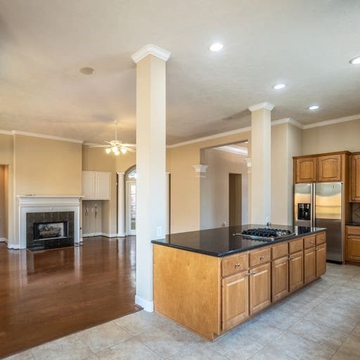 kitchen featuring brown cabinets, a ceiling fan, appliances with stainless steel finishes, a fireplace, and crown molding