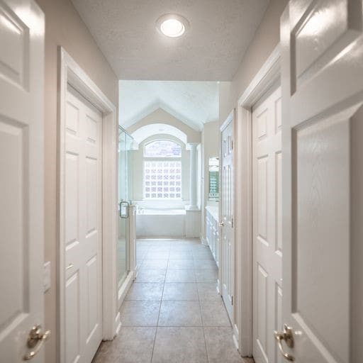 corridor with light tile patterned floors and vaulted ceiling