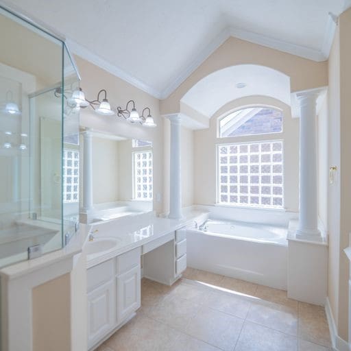 bathroom with crown molding, a garden tub, lofted ceiling, vanity, and ornate columns