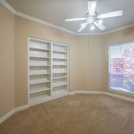 empty room featuring a ceiling fan, crown molding, baseboards, and carpet floors