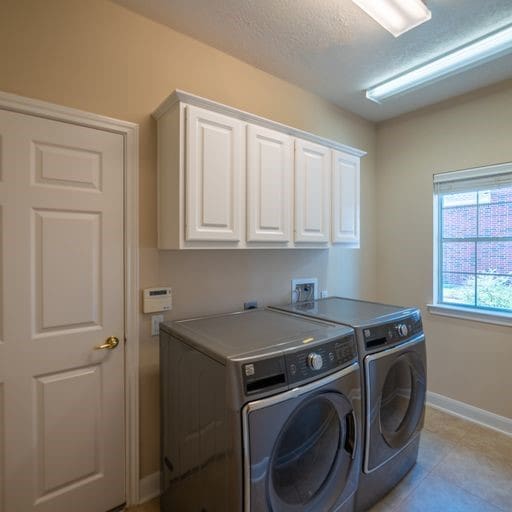 laundry area featuring light tile patterned floors, baseboards, cabinet space, a textured ceiling, and washing machine and dryer