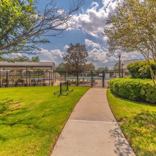 view of home's community with a yard, a swimming pool, and fence