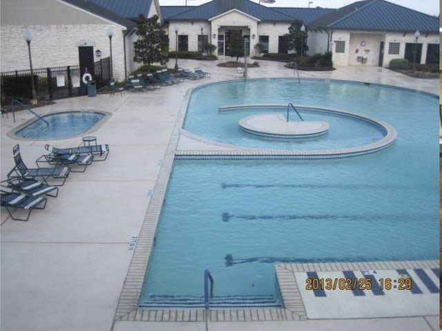 pool featuring a patio area, fence, and a hot tub