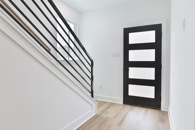 foyer entrance with stairway, light wood-style flooring, and baseboards