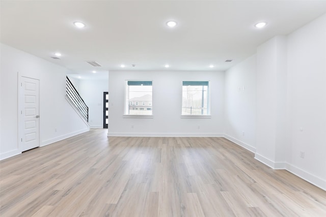 unfurnished living room featuring recessed lighting, stairway, baseboards, and light wood-style flooring