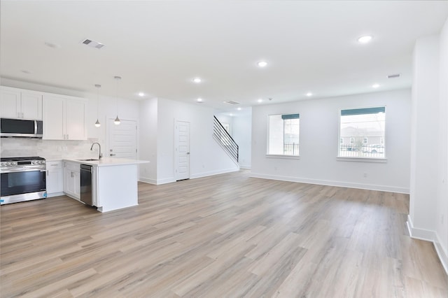 kitchen with visible vents, backsplash, light countertops, stainless steel appliances, and a sink