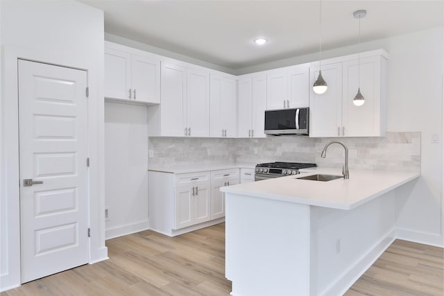 kitchen featuring a sink, stainless steel appliances, a peninsula, and light countertops