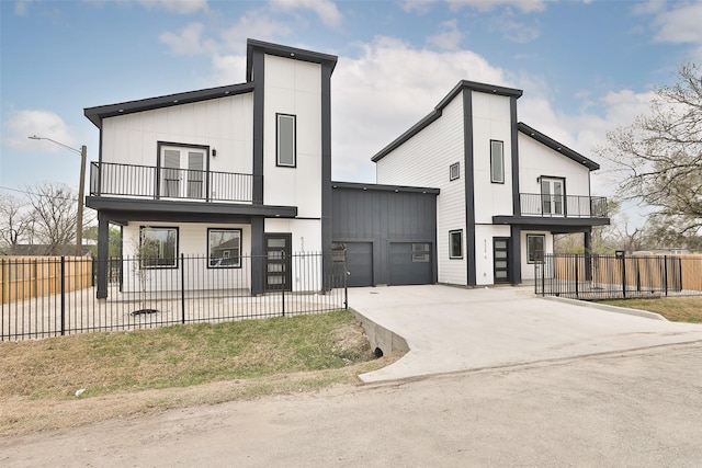 view of front of house featuring a garage, driveway, fence private yard, and a balcony