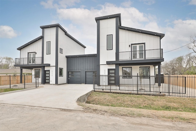 view of front of house featuring driveway, a fenced front yard, board and batten siding, an attached garage, and a balcony