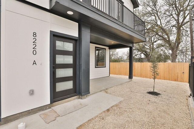doorway to property featuring fence, a patio area, and a balcony