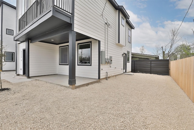 view of property exterior with a patio, a balcony, and fence