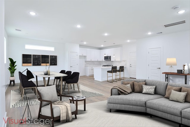 living room with baseboards, recessed lighting, visible vents, and light wood-type flooring
