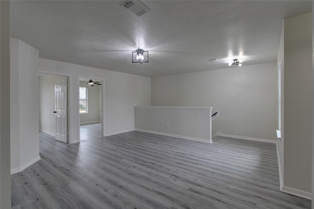 unfurnished room featuring wood finished floors, visible vents, and baseboards