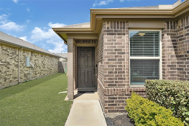 entrance to property with a yard and brick siding