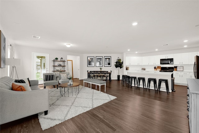 living area with recessed lighting, visible vents, and dark wood finished floors