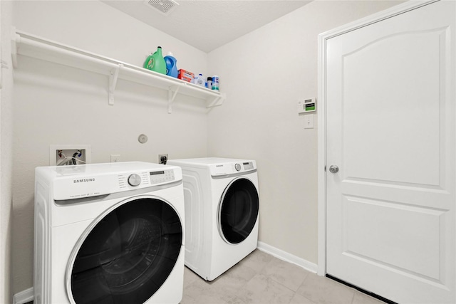 laundry area with laundry area, baseboards, visible vents, and washing machine and clothes dryer