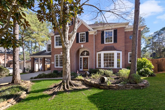 view of front of house with driveway, brick siding, a front lawn, and fence