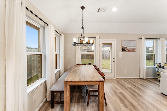 dining room featuring visible vents, light wood-style floors, baseboards, a chandelier, and vaulted ceiling