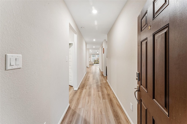 corridor featuring light wood-style flooring, recessed lighting, and baseboards