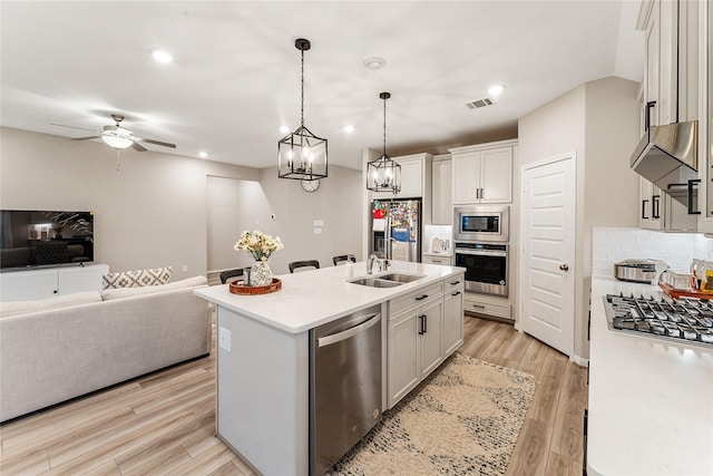 kitchen featuring visible vents, light wood-style flooring, a sink, appliances with stainless steel finishes, and open floor plan