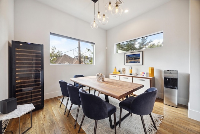 dining space with visible vents, light wood-style flooring, beverage cooler, and baseboards