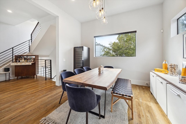 dining room featuring stairs, baseboards, and light wood finished floors