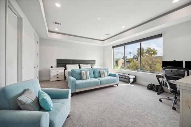 bedroom with a tray ceiling, carpet flooring, and visible vents