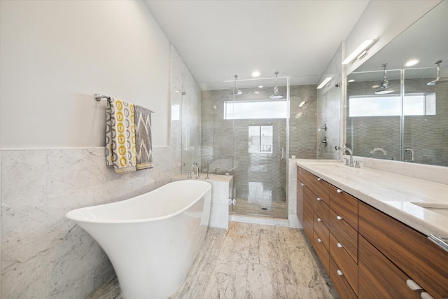 full bathroom with double vanity, a stall shower, a freestanding bath, a sink, and marble finish floor