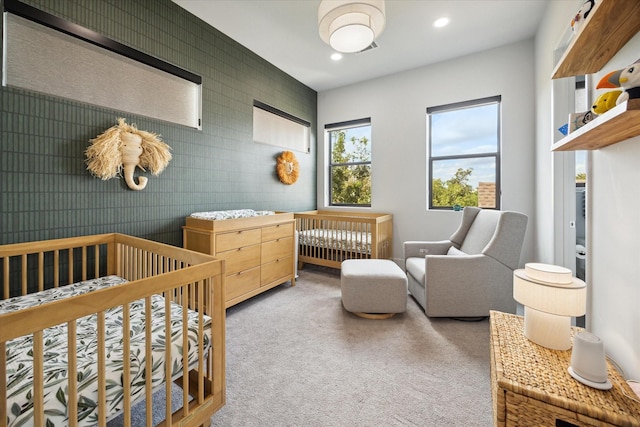 carpeted bedroom featuring recessed lighting and a crib