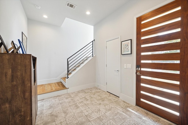 foyer entrance with visible vents, recessed lighting, stairway, and baseboards