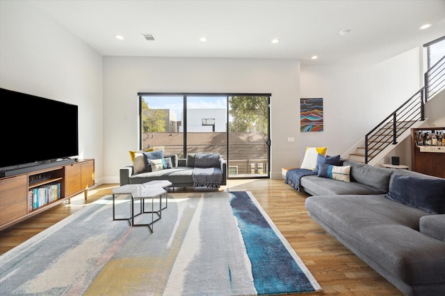 living room featuring visible vents, baseboards, stairs, recessed lighting, and wood finished floors