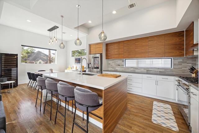 kitchen with visible vents, modern cabinets, a sink, wood finished floors, and a breakfast bar area